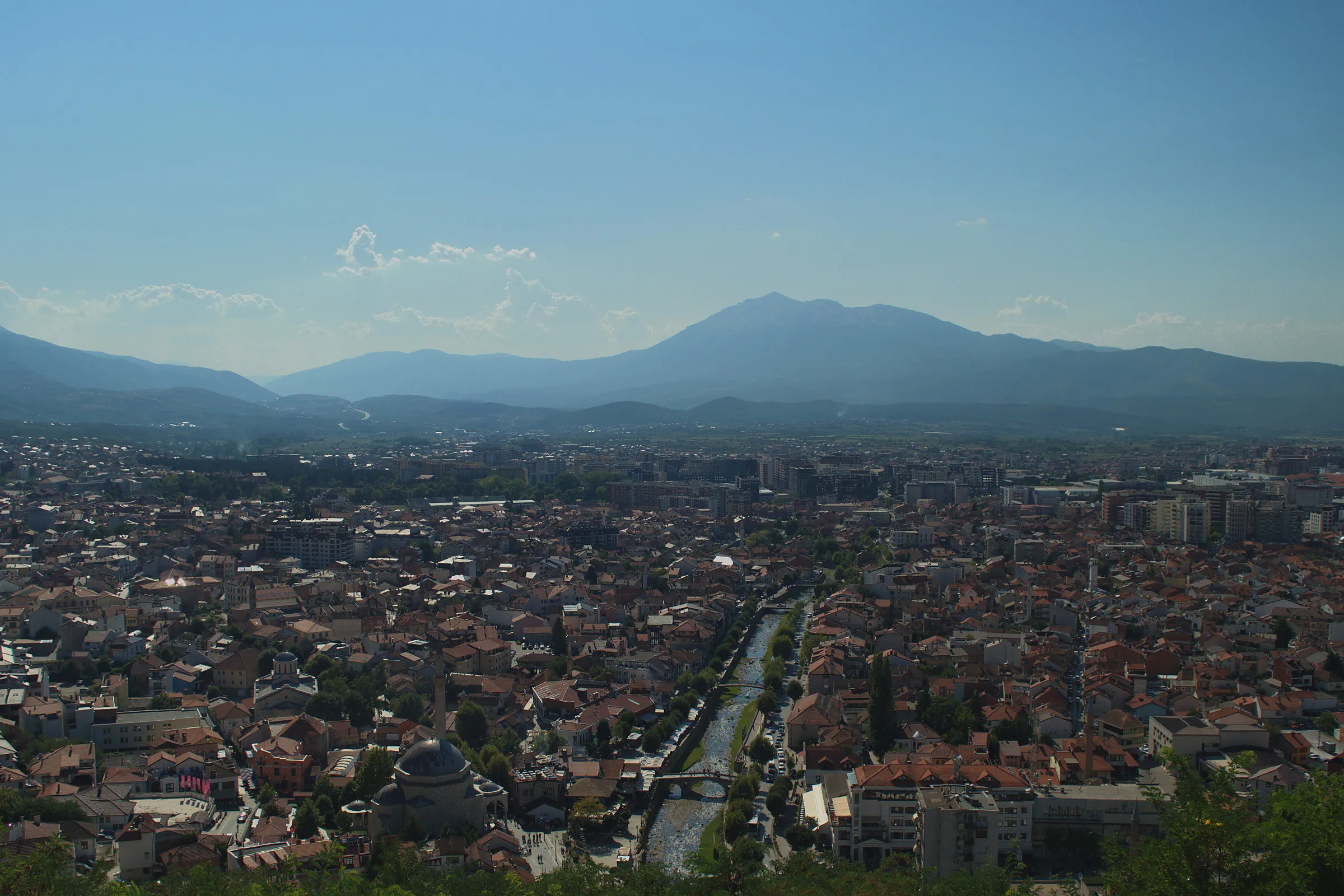 Prizren vista dall'alto: i tetti della città attraversata dal fiume, il minareto della moschea e le montagne sullo sfondo